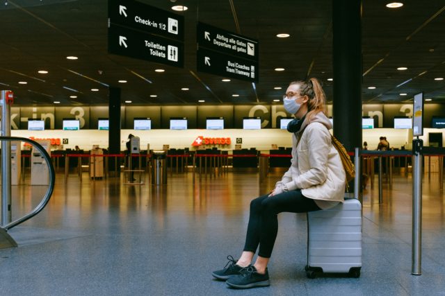 Girl waiting on suitcase to travel in Covid